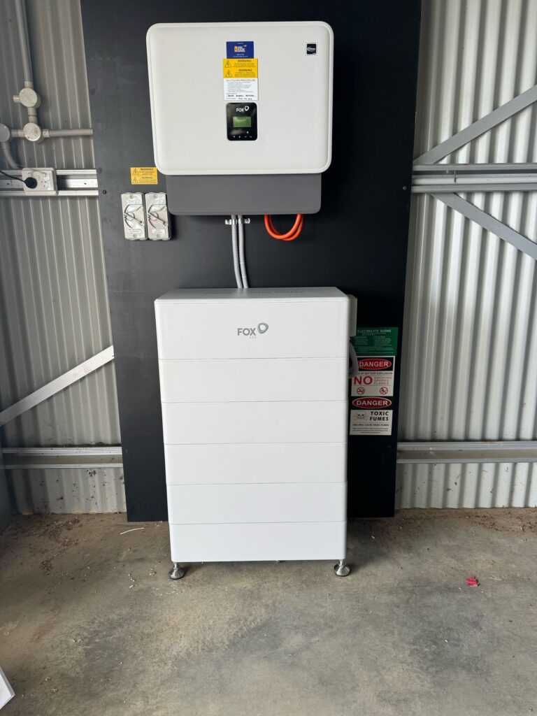 Fox ESS inverter and stacked home battery installed on a shed wall